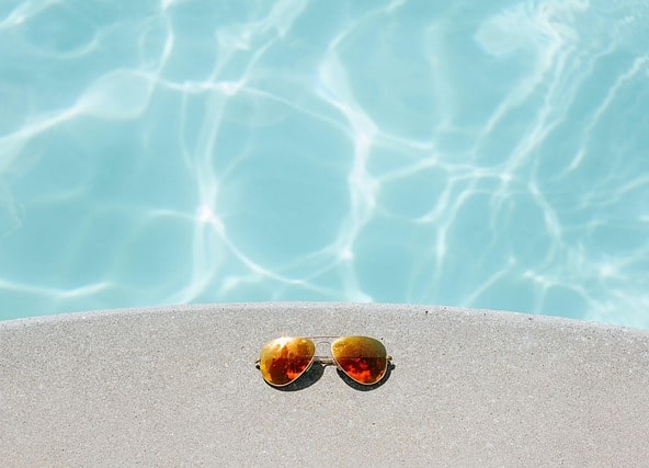 los imprescindibles para cuidar tu piscina. Gafas de sol en una piscina.